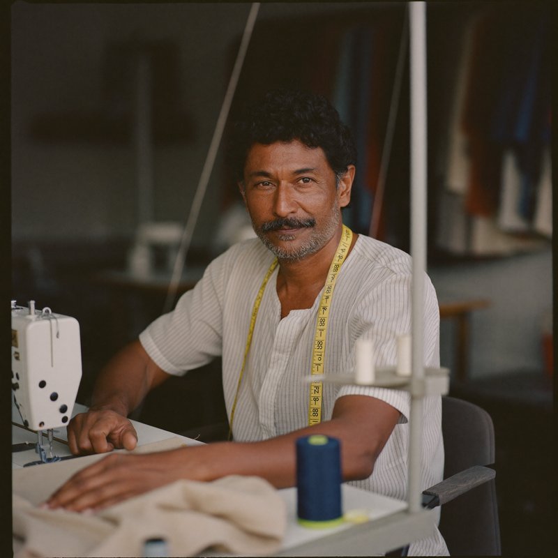 A tailor at his sewing machine in a small alterations shop.